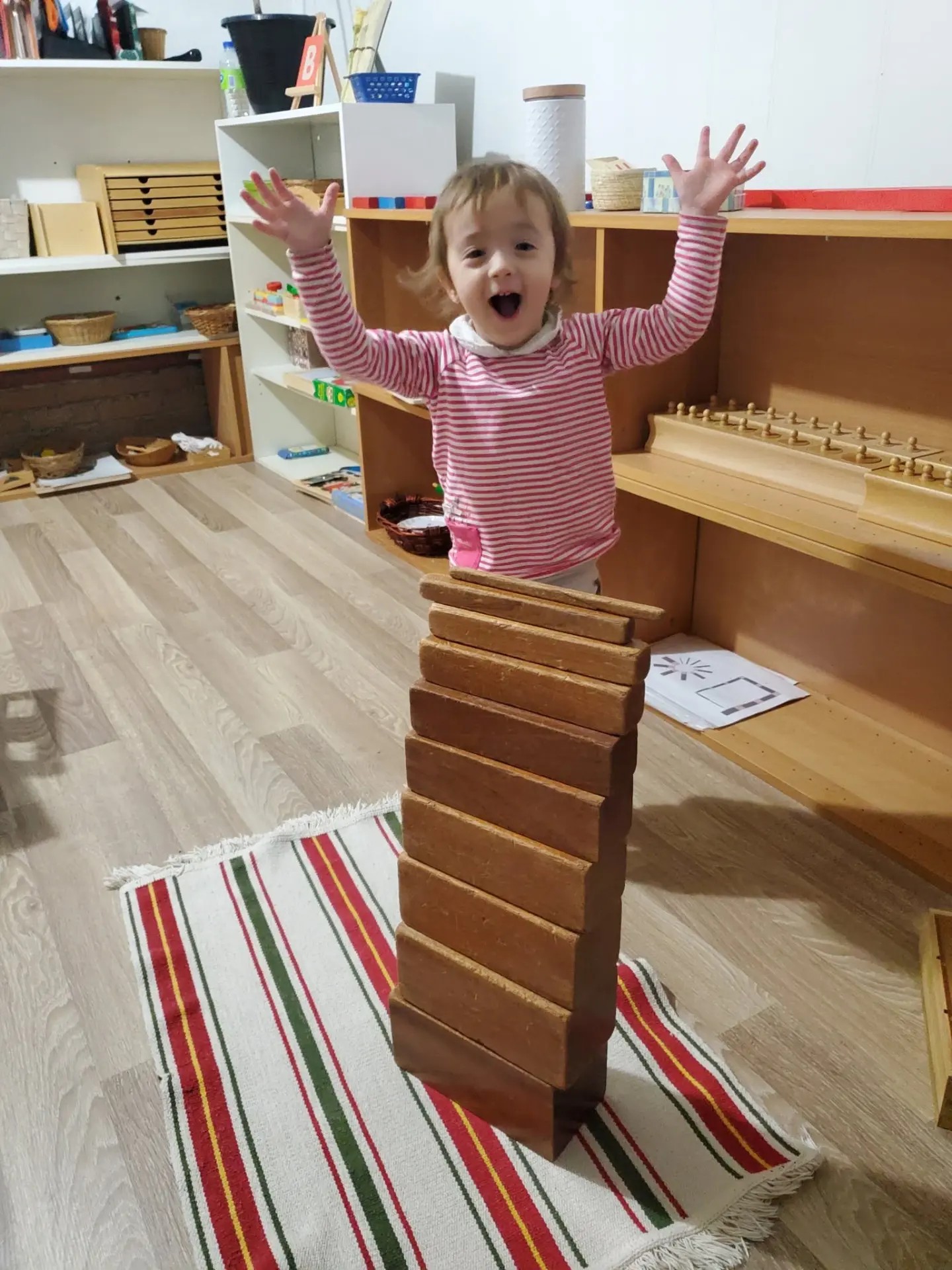 Enfant fier devant sa tour de blocs Montessori à la garderie Les Aventuriers d'Anjou